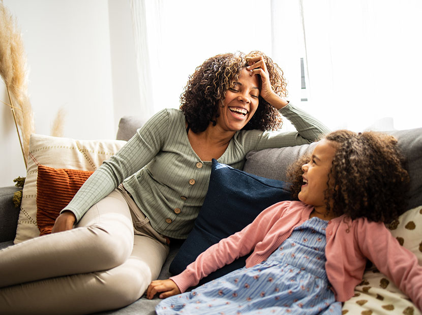 Mother and daughter on couch laughing